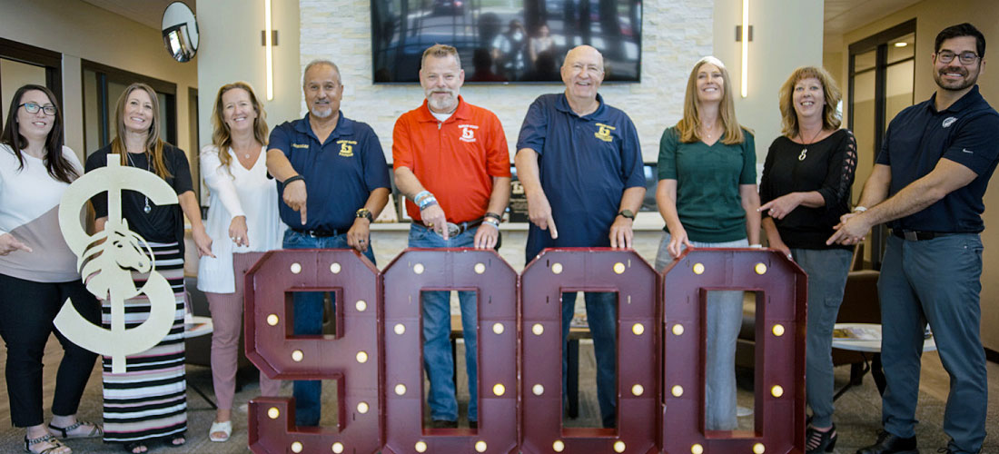 First Federal employees and members of Warrior Wishes pointing at $9000 marquee numbers.