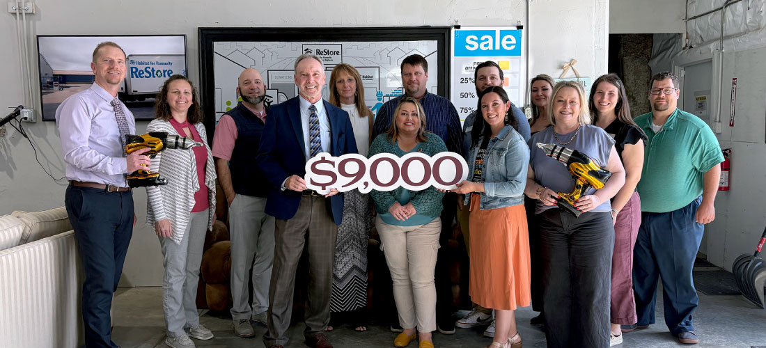 Group of First Federal employees and Habitat for Humanity members holding a $9,000 sign