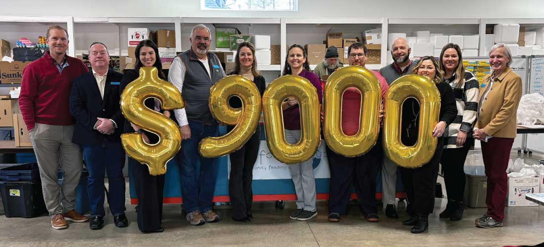 Group of people holding "$9,000" balloons at the Food Group.