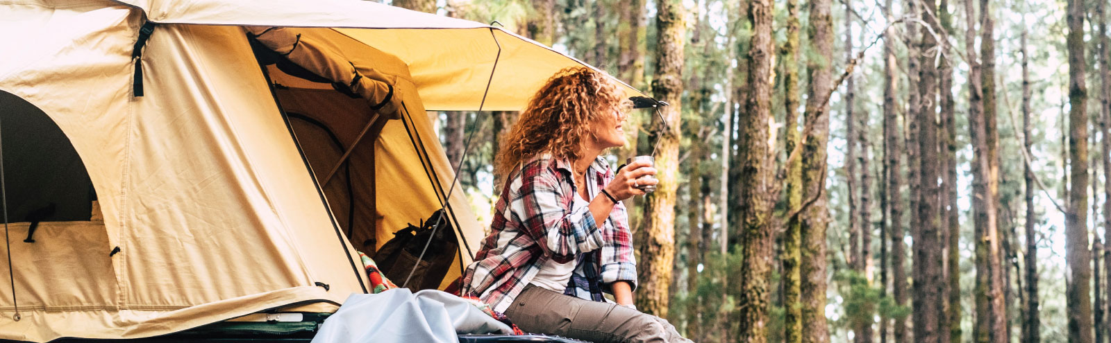 Woman drinking coffee while camping in the forest.