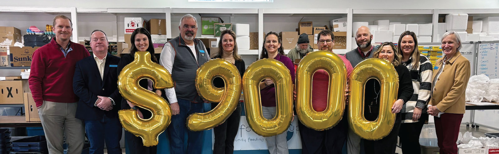 Group of people holding $9000 balloons at The Food Group.