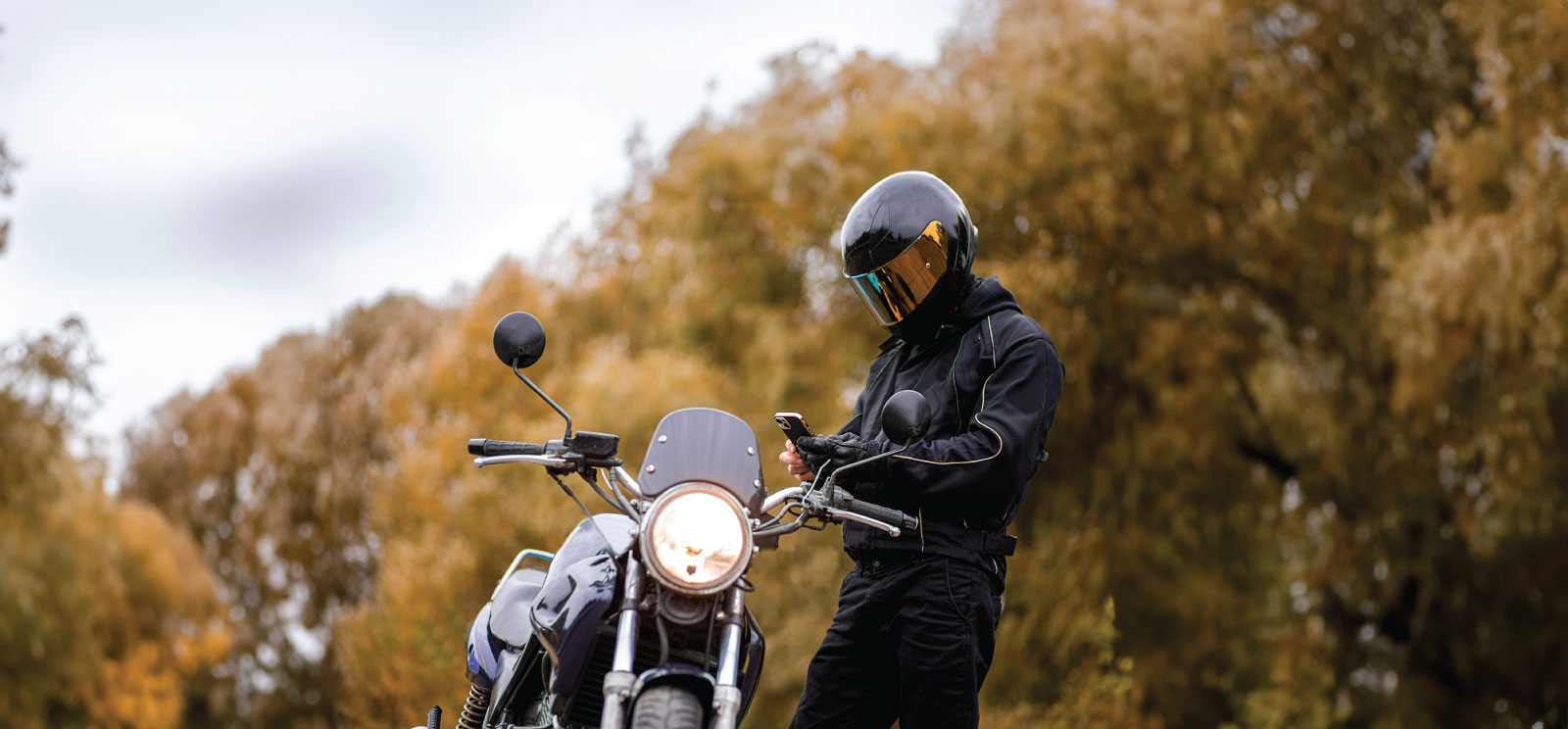 Person checking mobile phone next to motorcycle.