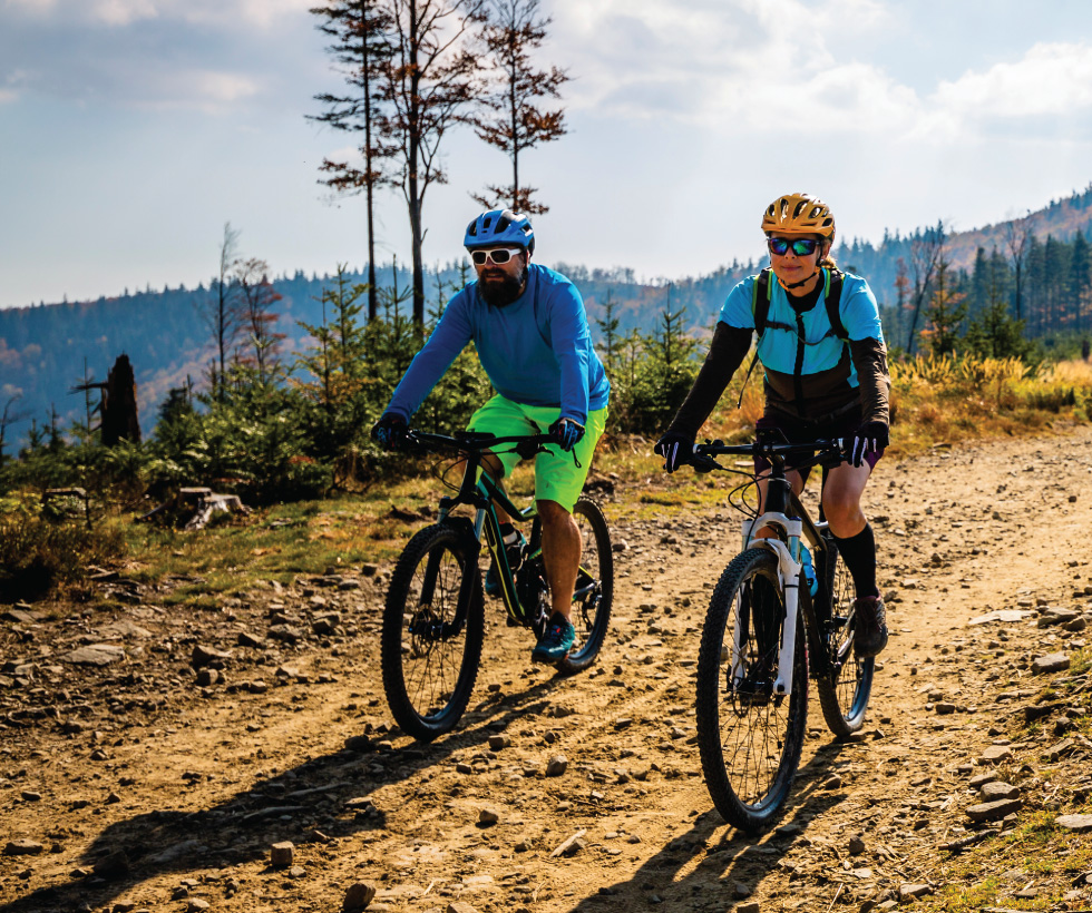 Two people biking on a rocky mountain path.