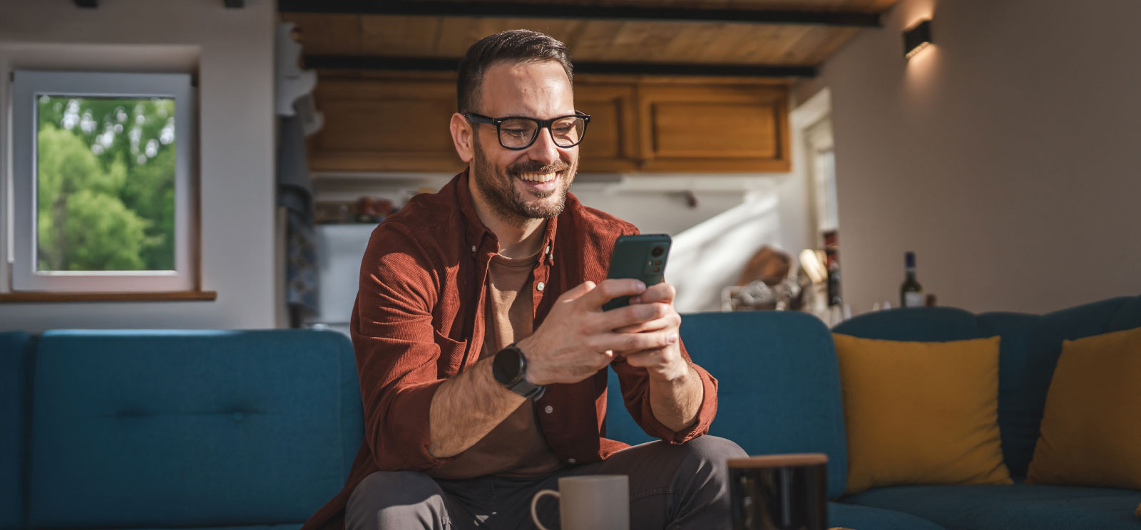 Man sitting on his couch looking at his cell phone