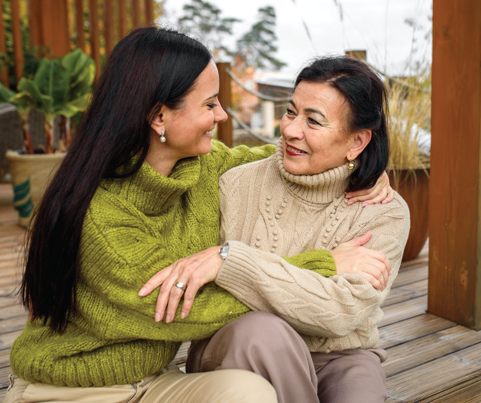 Mother and daughter embracing on porch.