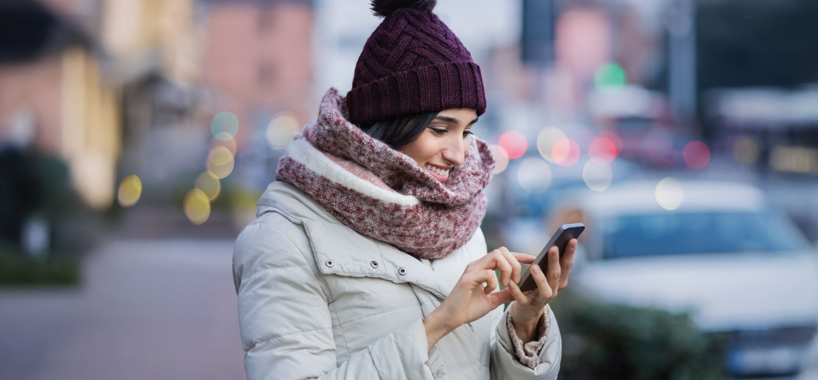 Woman downtown using a mobile phone in winter clothing.