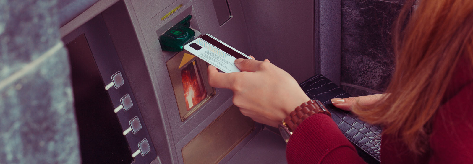 Hand of a person putting a card into an ATM.