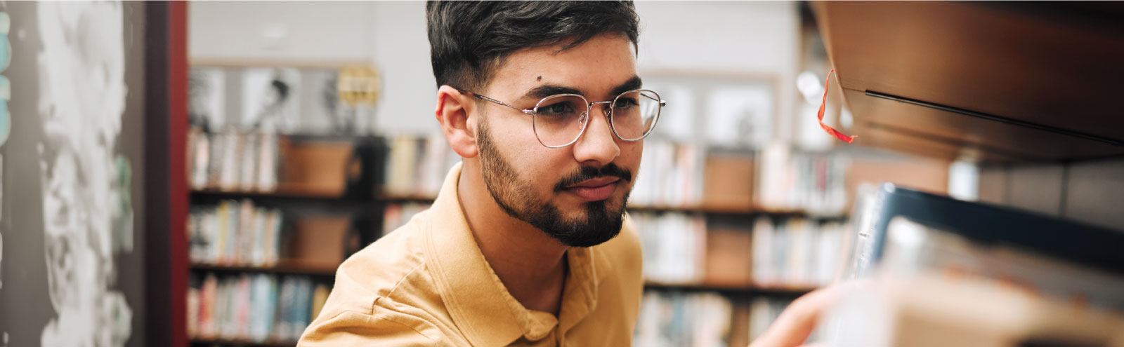 Man at a library searching through books.