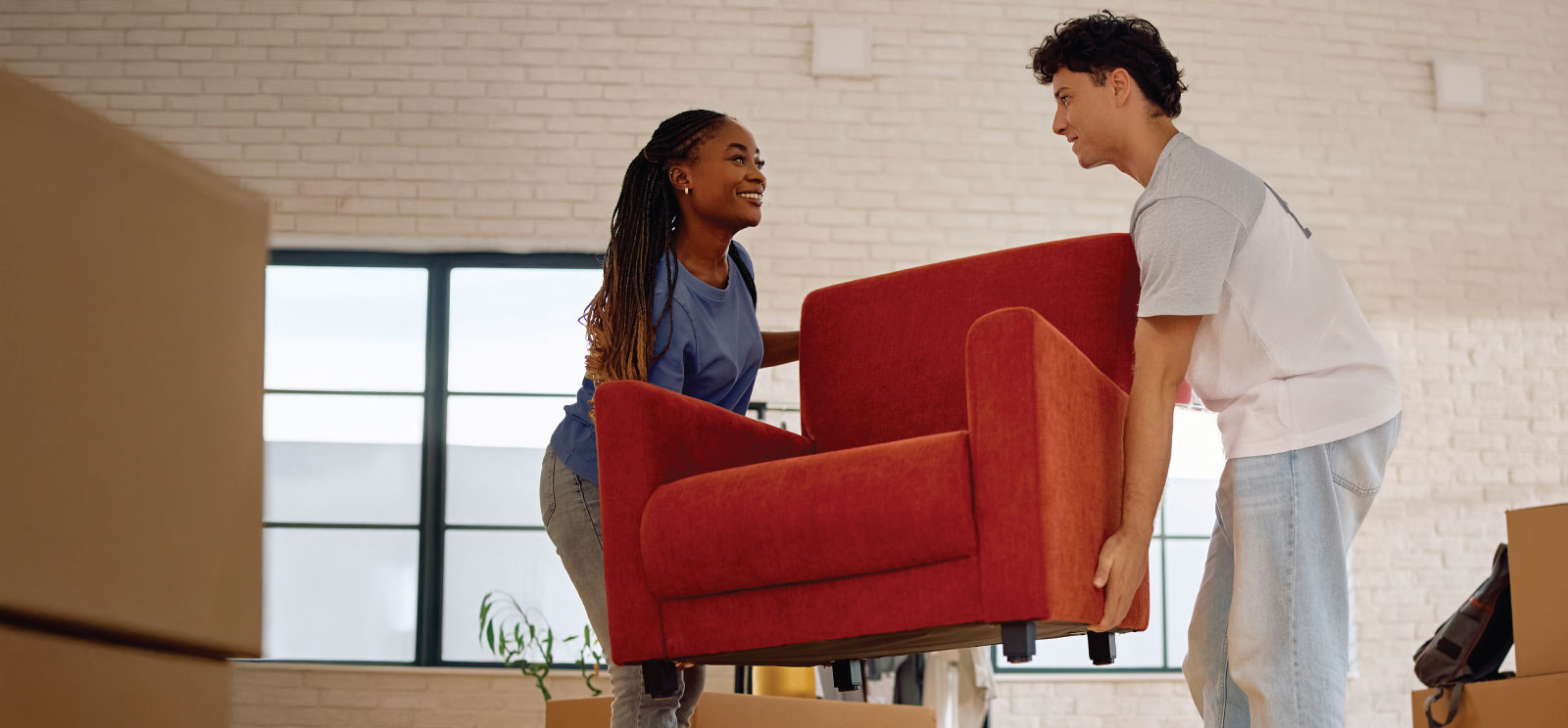 Young couple moving a chair into their new home.