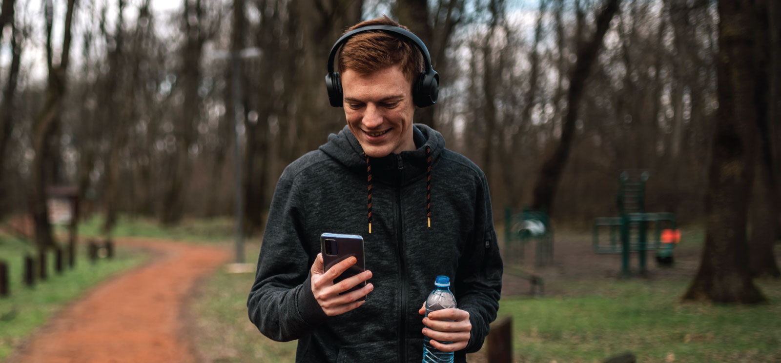 Jogger looking at his mobile phone outside.