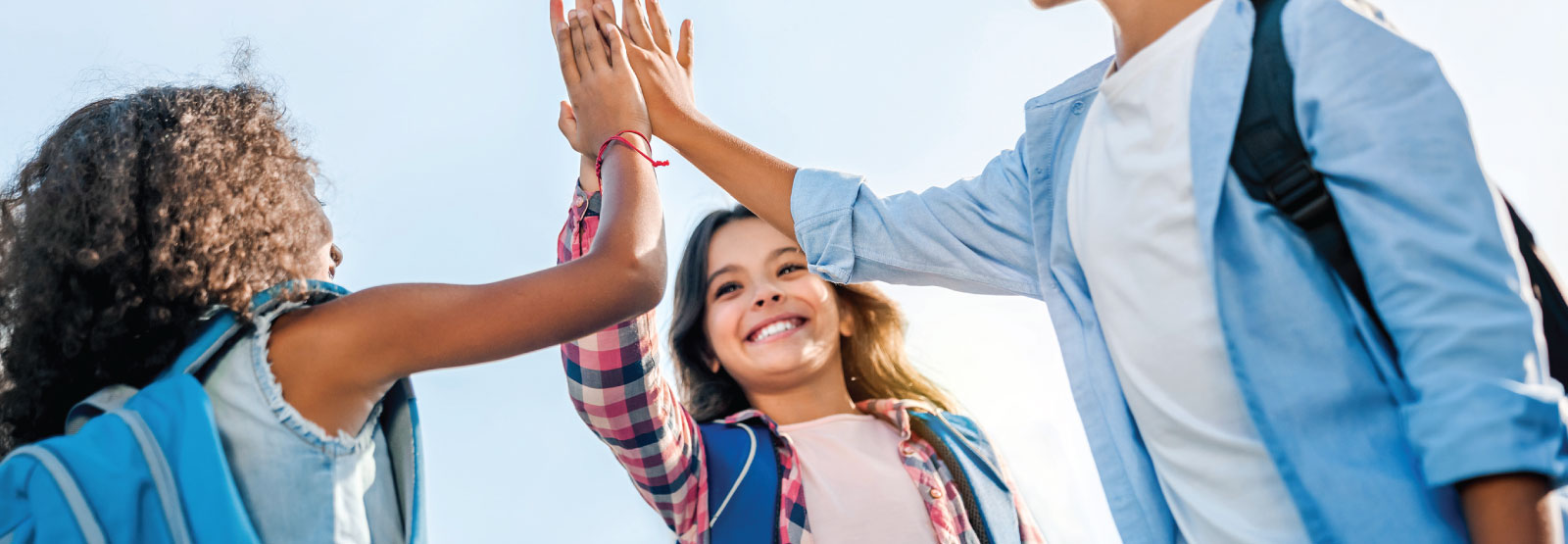 Three school-aged kids high-fiving.