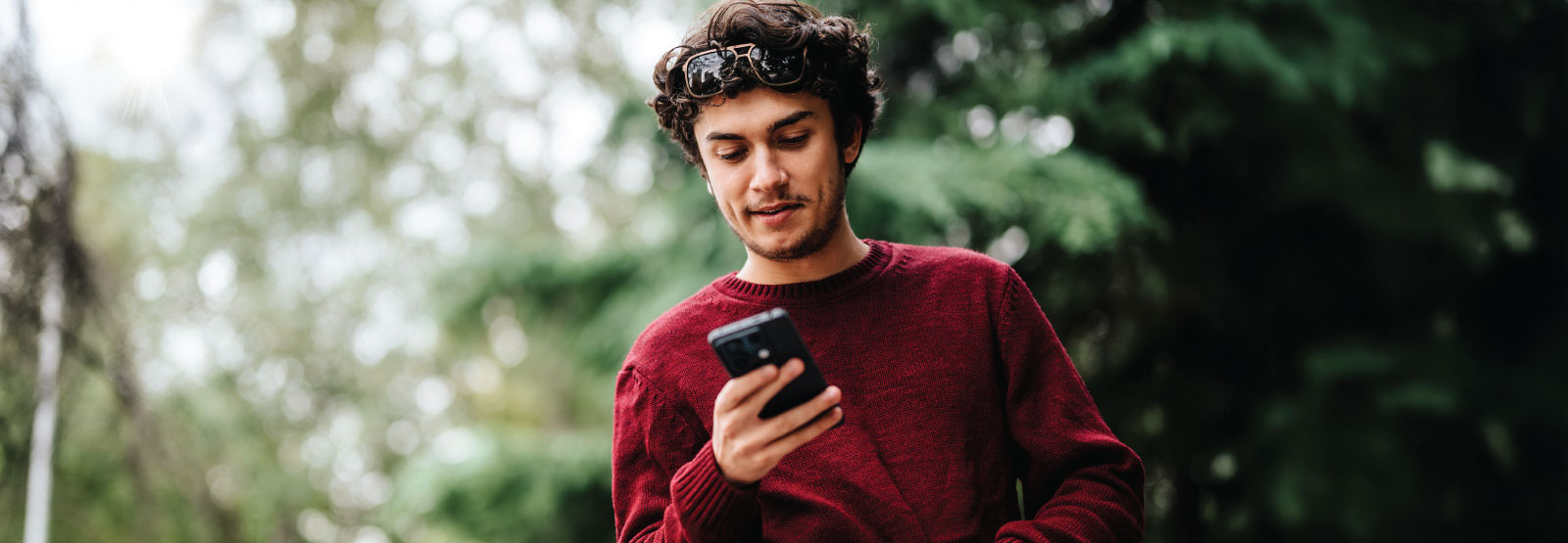 Man in park looking at mobile phone.