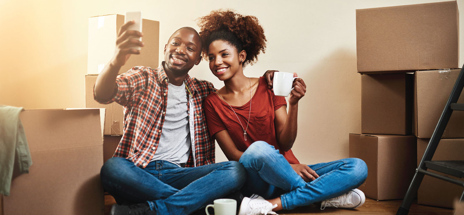 Couple taking a selfie among moving boxes in new home.